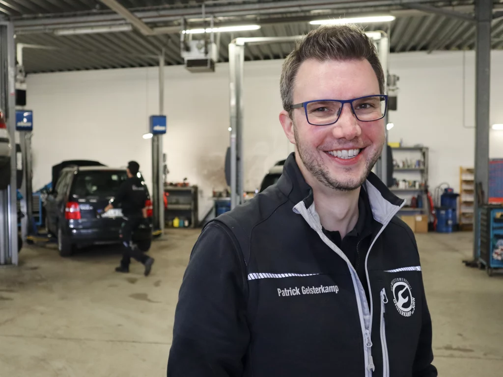 Patrick Gelsterkamp, der Geschäftsführer und Werkstattmeister von Gelsterkamp und Sohn, lächelnd in der Kfz-Werkstatt.
